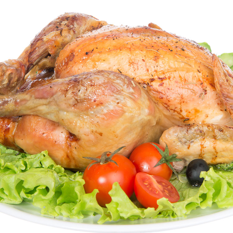 Garnished roasted thanksgiving chicken on a plate decorated with salad, olives, tomatoes, cucumbers isolated on a white background